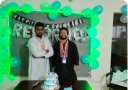Two people standing infront of Reformedtech anniversary decoration